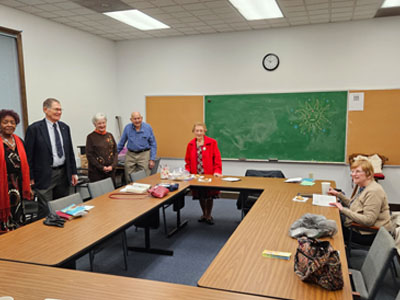 Adults standing around rectangle tables for Bible study